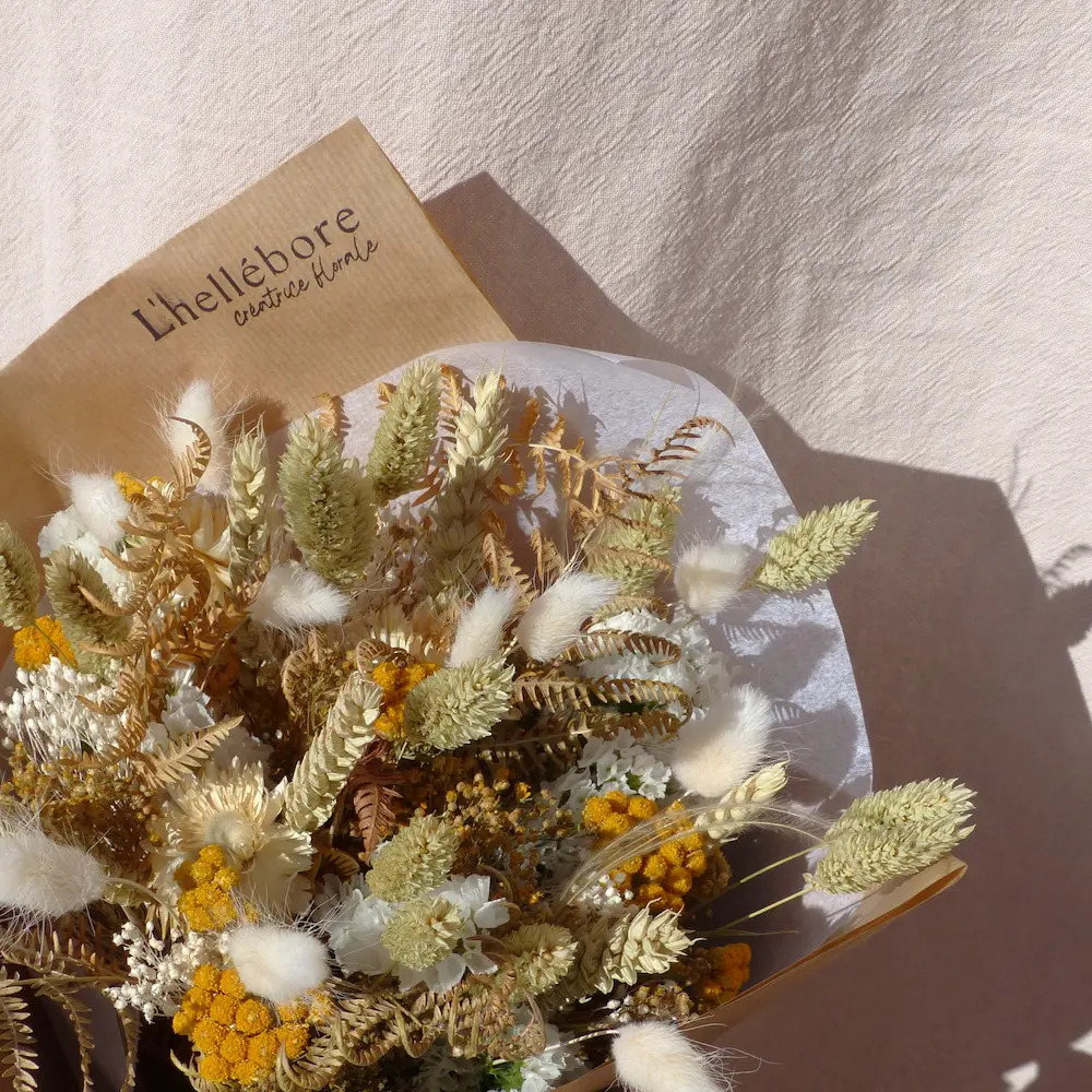 Bouquet de fleurs séchées jaune et blanc, emballé dans du papier kraft