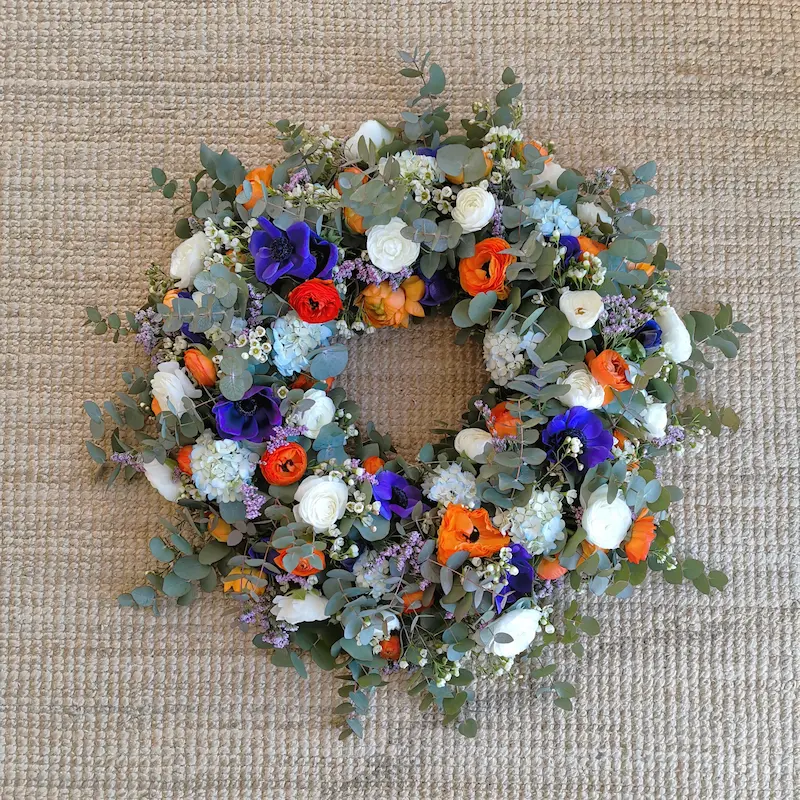 Couronne deuil fleurs oranges et violettes avec feuillage d'eucalyptus