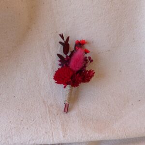 Boutonnière de la gamme Laura, tons rouge et bordeaux.