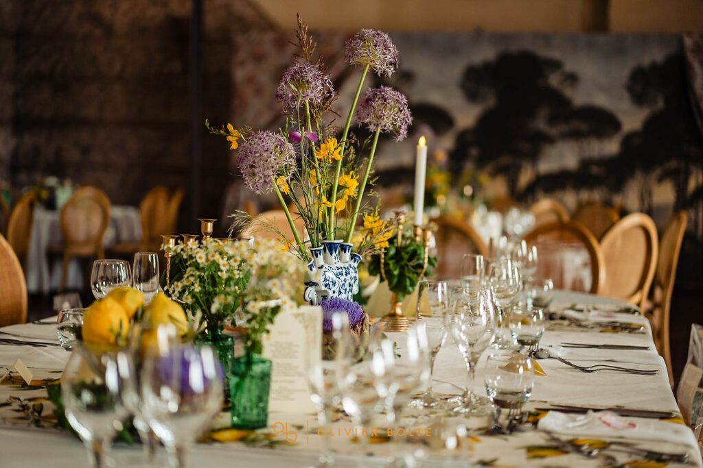 Table de mariage, avec compositions de fleurs dans les tons jaune, violet et blanc