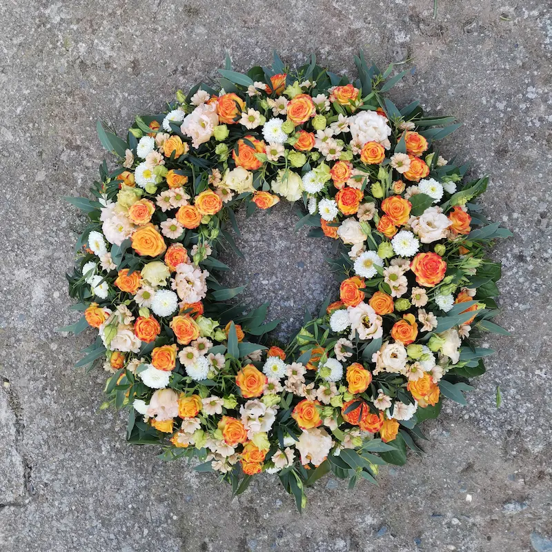 Couronne de fleurs dans les tons orange, blanc et saumon