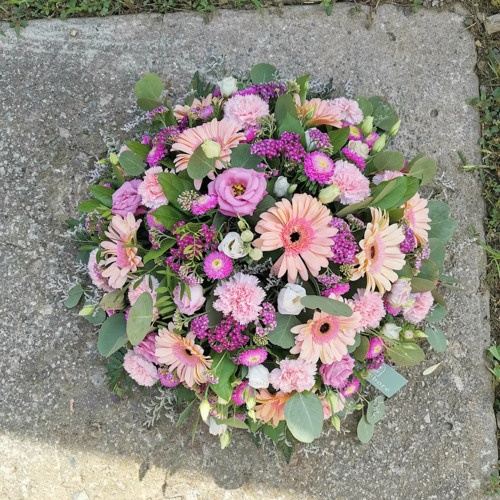 Coussin de fleurs deuil dans des tons pastels roses, blancs et vert